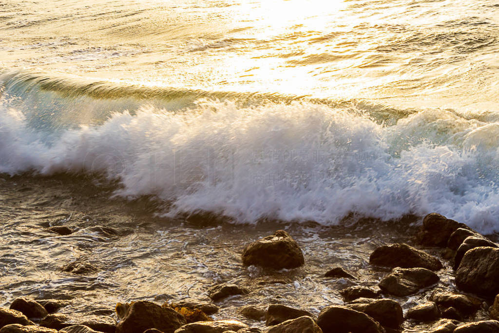 wave breaking on rocks at shoreline with sunrise