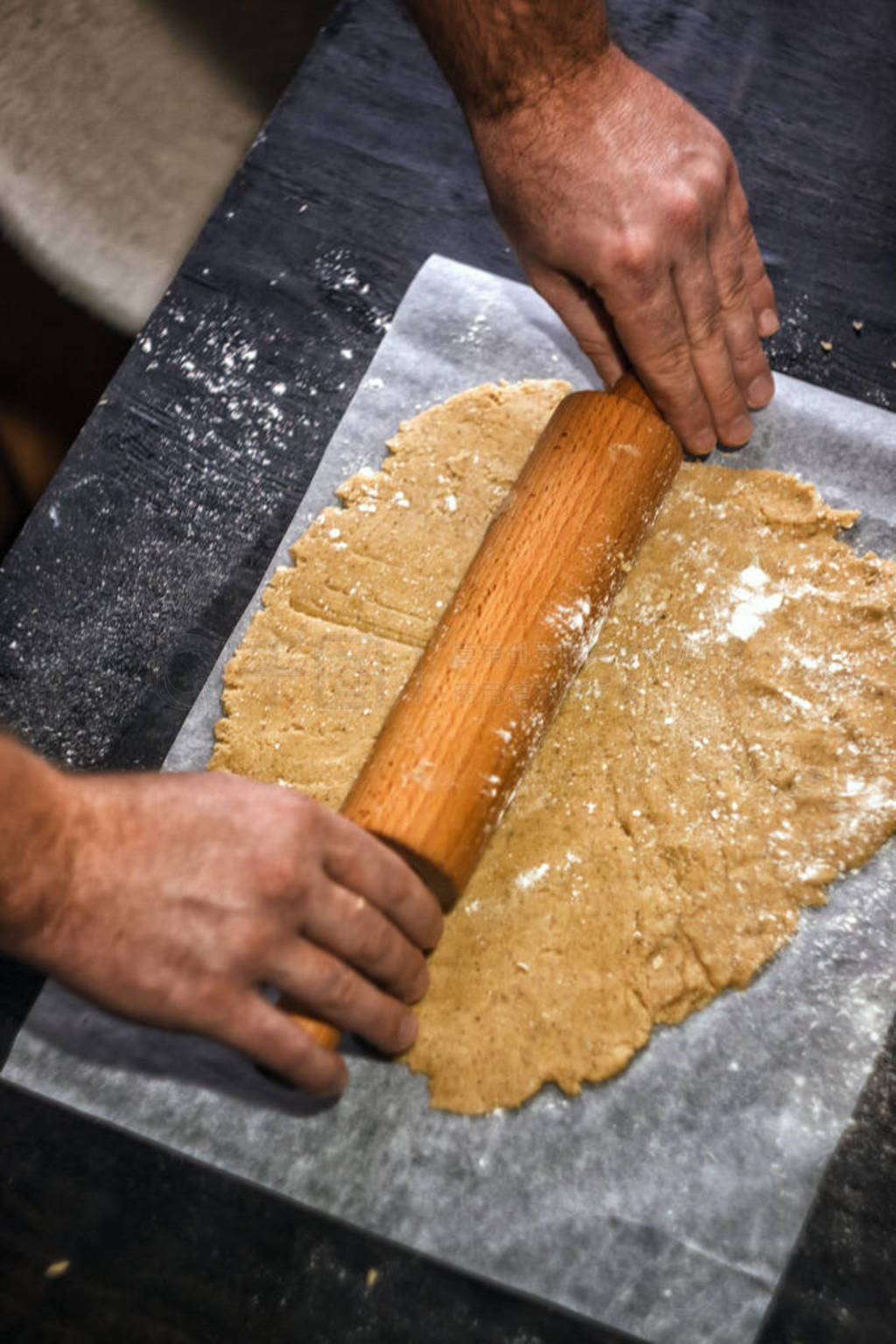 Male hands roll out shortbread gingerbread dough. Close-up, top