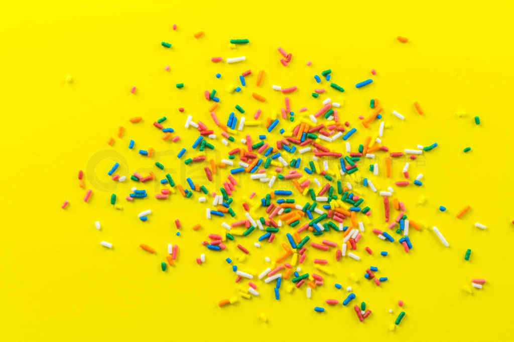 Multi-coloured sprinkles on bright yellow background