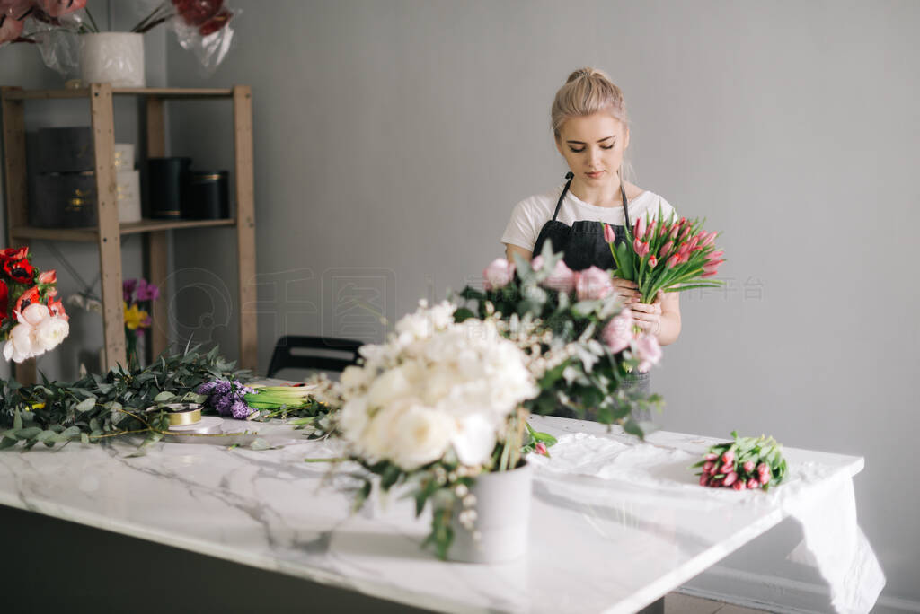 Professional young woman florist wearing apron making floral arr