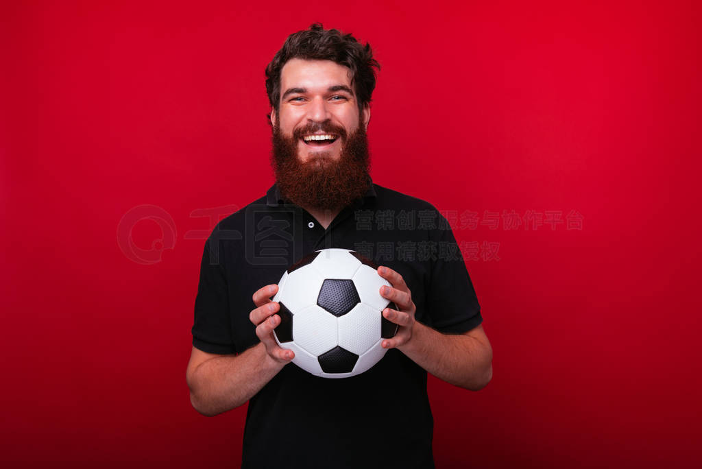 Photo of bearded supporter, holding a soccer ball while looking