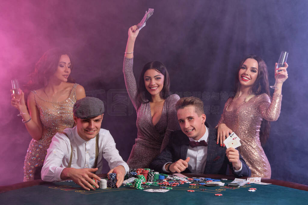 Friends playing poker at casino, at table with stacks of chips,