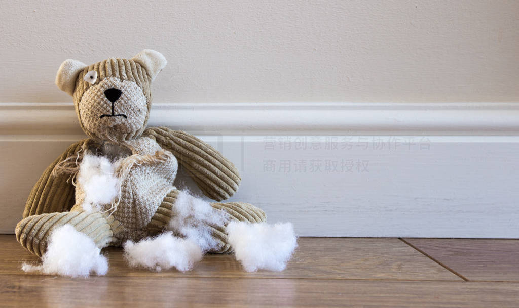 s teddy bear sitting alone on a cold floor with a ripped and tor