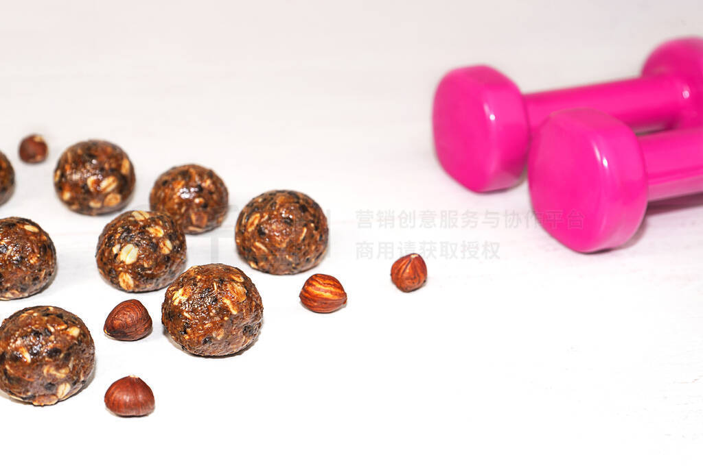 Energy balls and pink dumbbells on gray wood background.