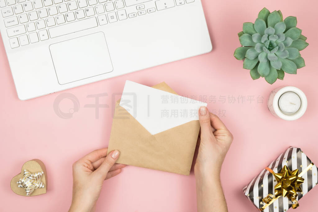 Womans hands holding craft envelope with copyspace on pink paste