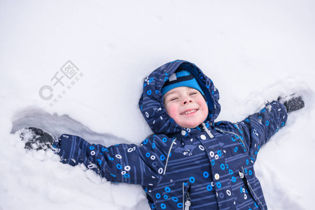 可爱的小小孩男孩在多彩冬季服装制作雪天使，躺在。与孩子们在户外活动休闲。快乐的孩子