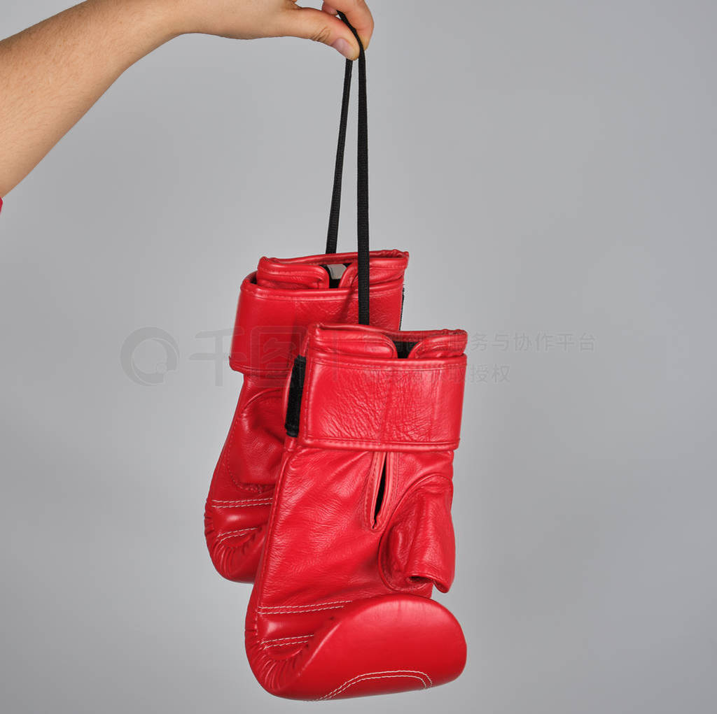 pair of red leather boxing gloves hang on a string