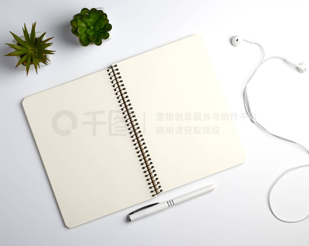 spiral notebook with empty sheets, pen and green plants