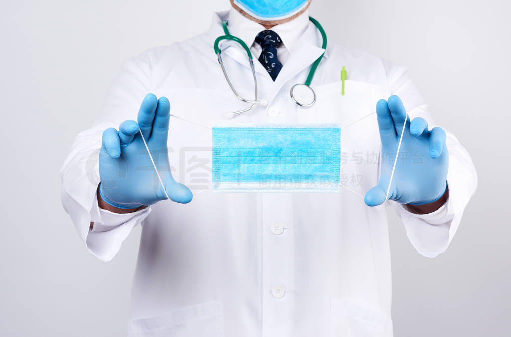 doctor in a white coat, blue latex sterile gloves holds textile