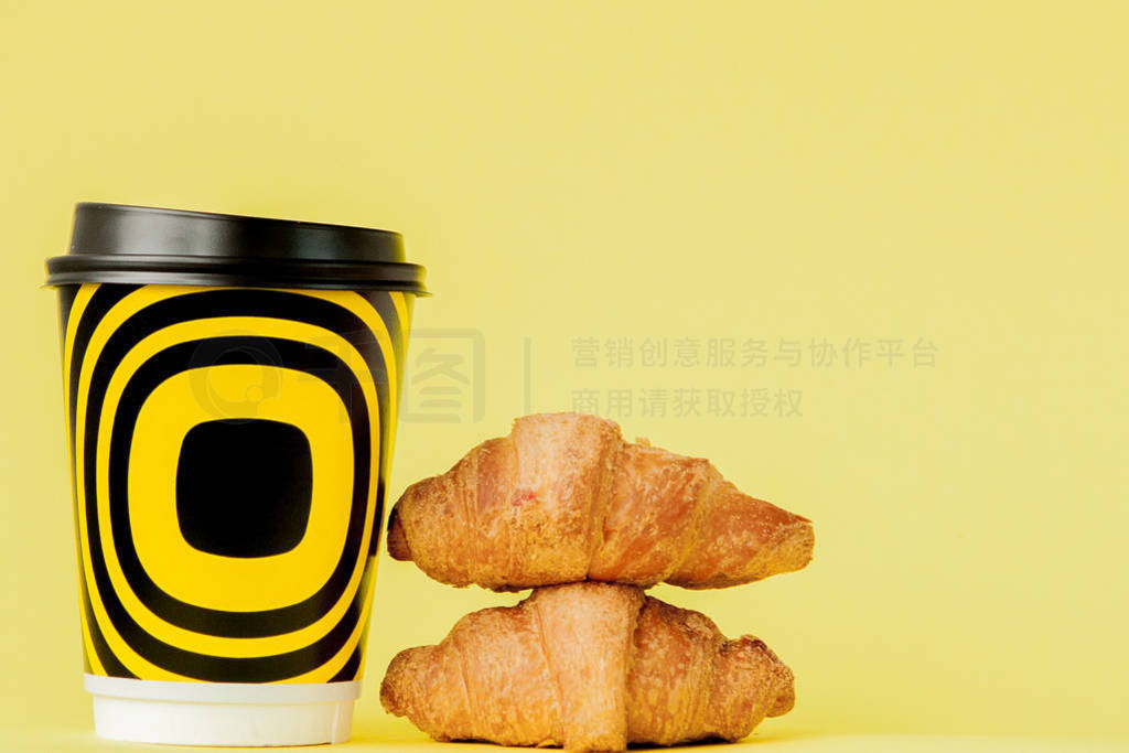 Paper cup of coffee and croissants on a yellow background, Copy