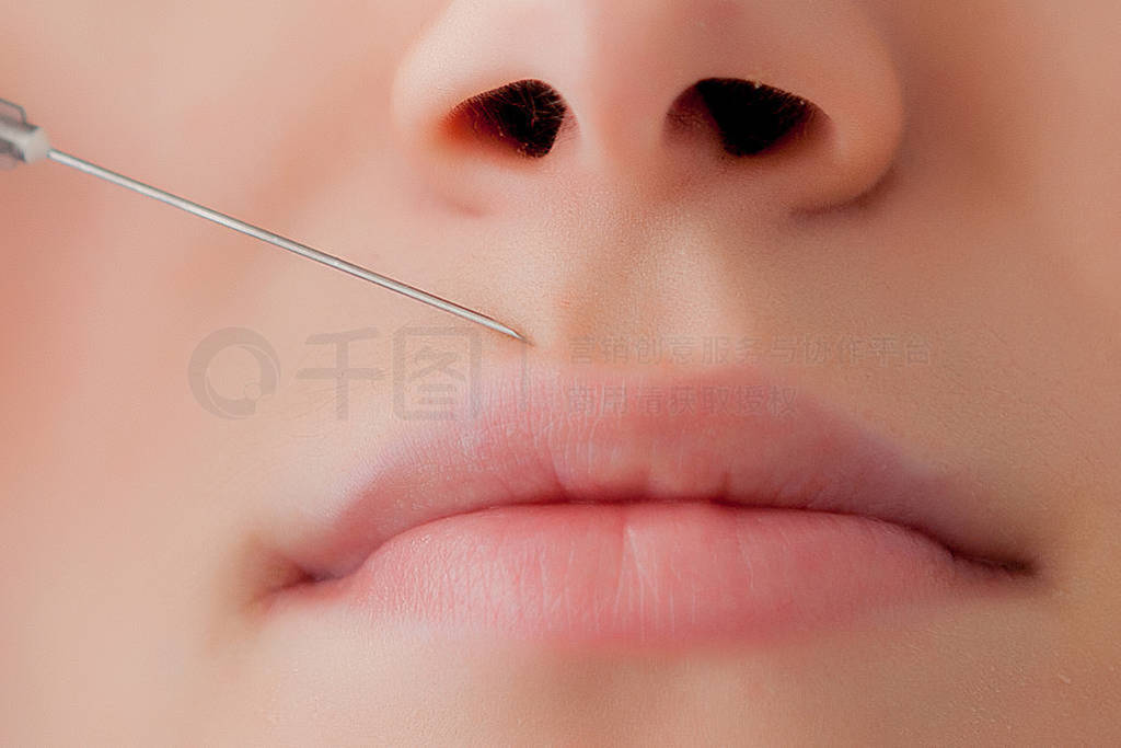 Doctor in gloves giving woman botox injections in lips, on pink