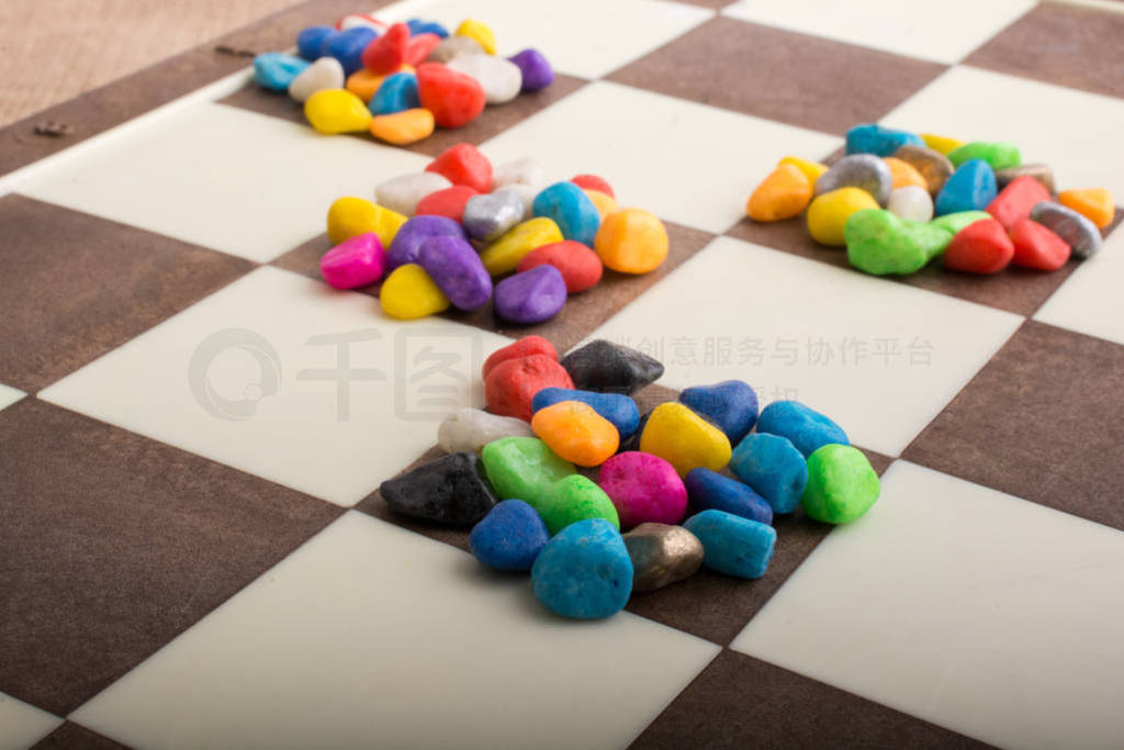 Colorful pebbles spread on checked board