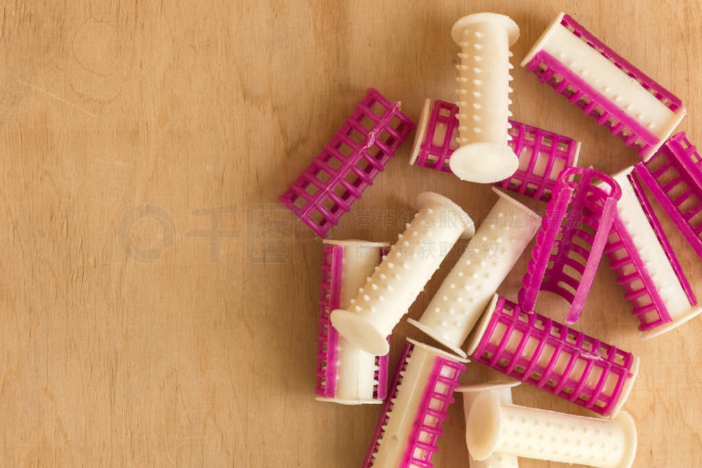 Heap of curlers on wooden background top view.