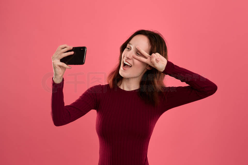 Photo of a pretty young brunette woman making selfie with a mobi