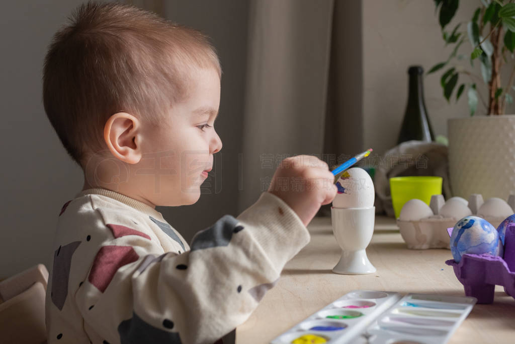 Toddler boy painting easter eggs preparing for holidays. Easter
