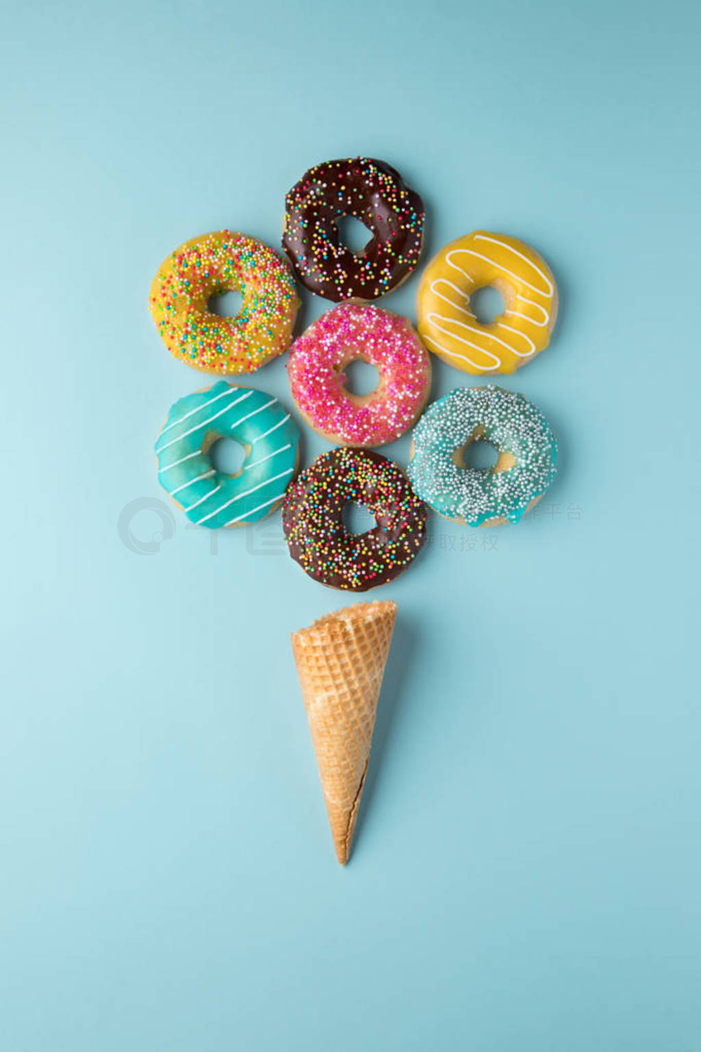 Colorful donuts in ice-cream shape with waffle cone on light blu