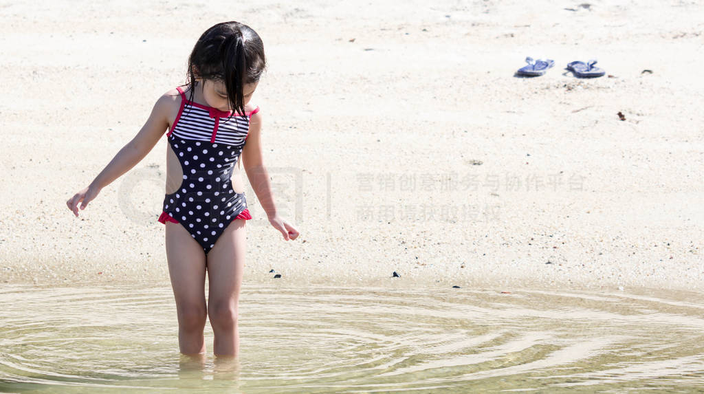 cute asian female toddler child while playing on sand and water