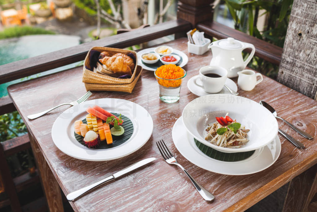 Breakfast with balinese fruit plate, basket with croissants and
