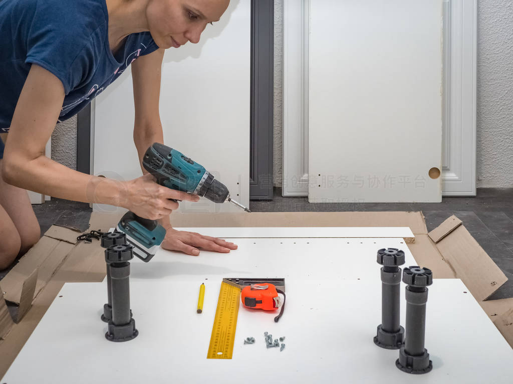 Female with a cordless driver collects furniture.