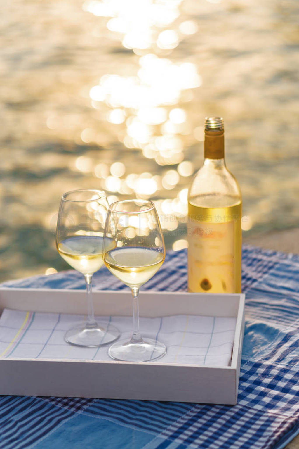Sunset view of two wine glasses and bottle of white wine on the