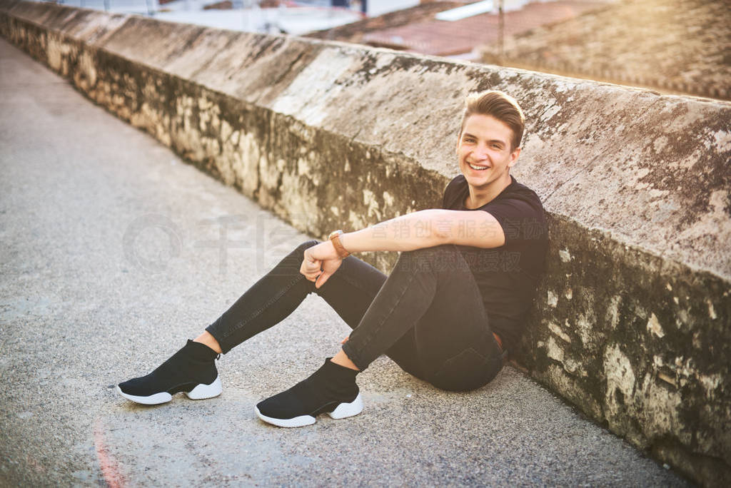 Elegant smiling young man in black posing on the street