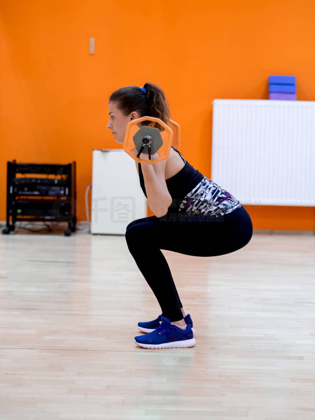 Young model girl makes exercises at the gym in front of mirror