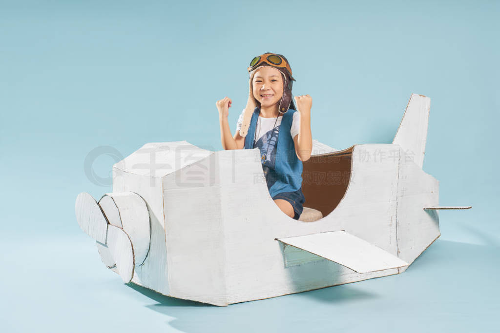 Little cute girl playing with a cardboard airplane.