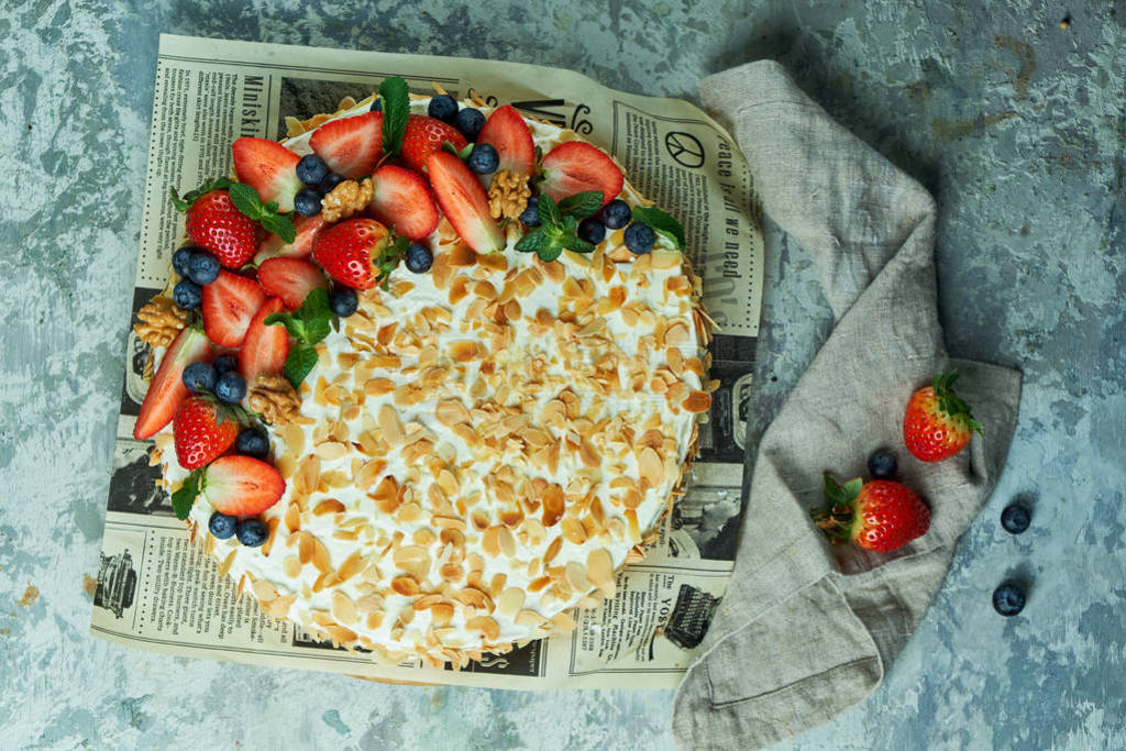 Strawberry meringue cake with almond petals, on newspaper