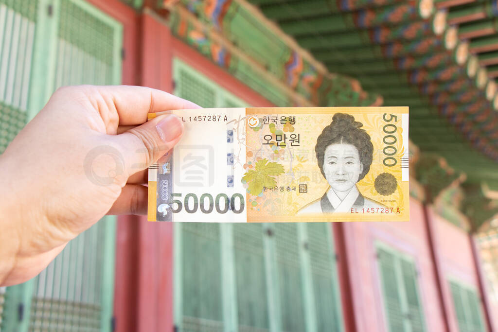 Traveller hand hold 50000 korean won banknote on defocused Korea
