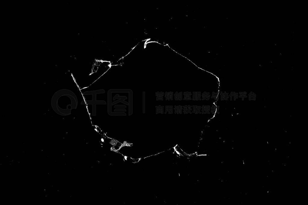 hole in the glass with cracks isolated on a black background.