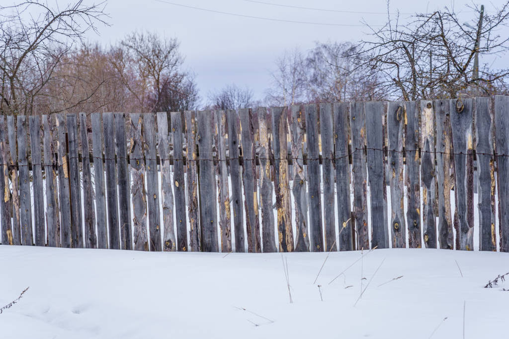 fence around the garden of unpainted boards