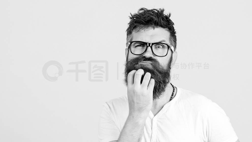Pensive man touching his beard on white wall. Handsome man in gl