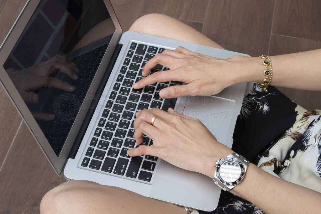 Hands of woman wearing smartwatch on the keyboard of her laptop