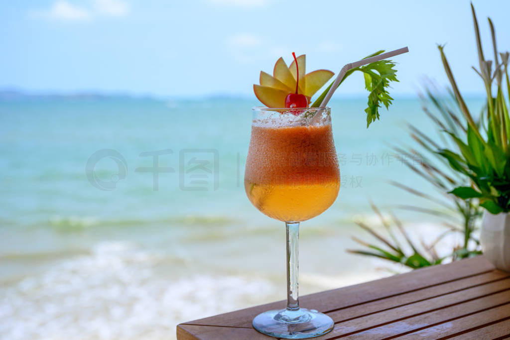 Apple mocktail with cherry in wine glass in tropical sea