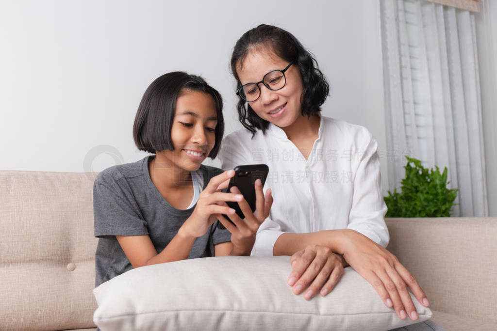 Asian mother and her little daughter using smartphone and smile