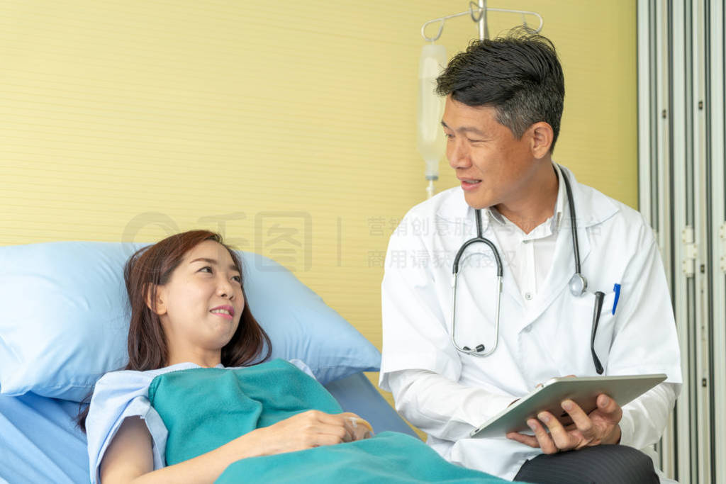 Asian senior doctor sitting on hospital bed and discussing with