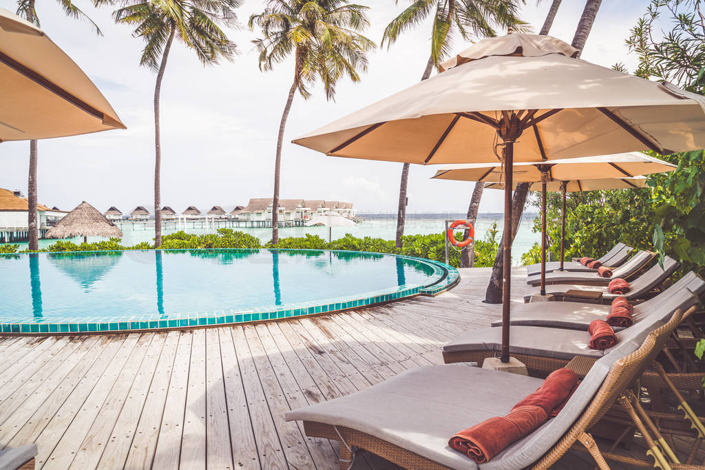 Umbrella and chair around swimming pool in resort hotel