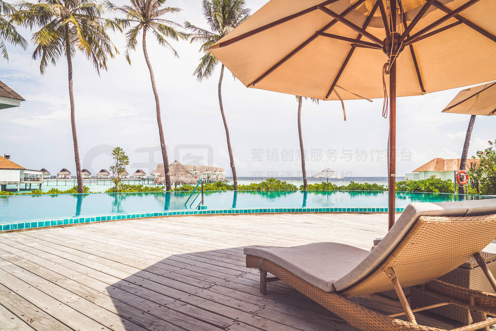 Umbrella and chair around swimming pool in resort hotel