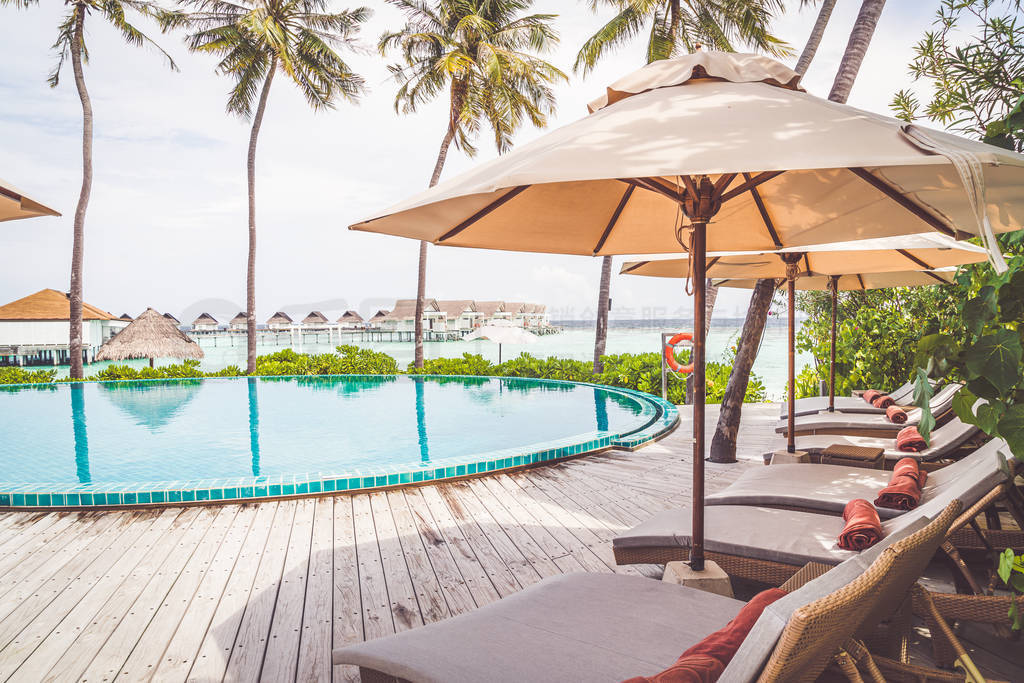 Umbrella and chair around swimming pool in resort hotel