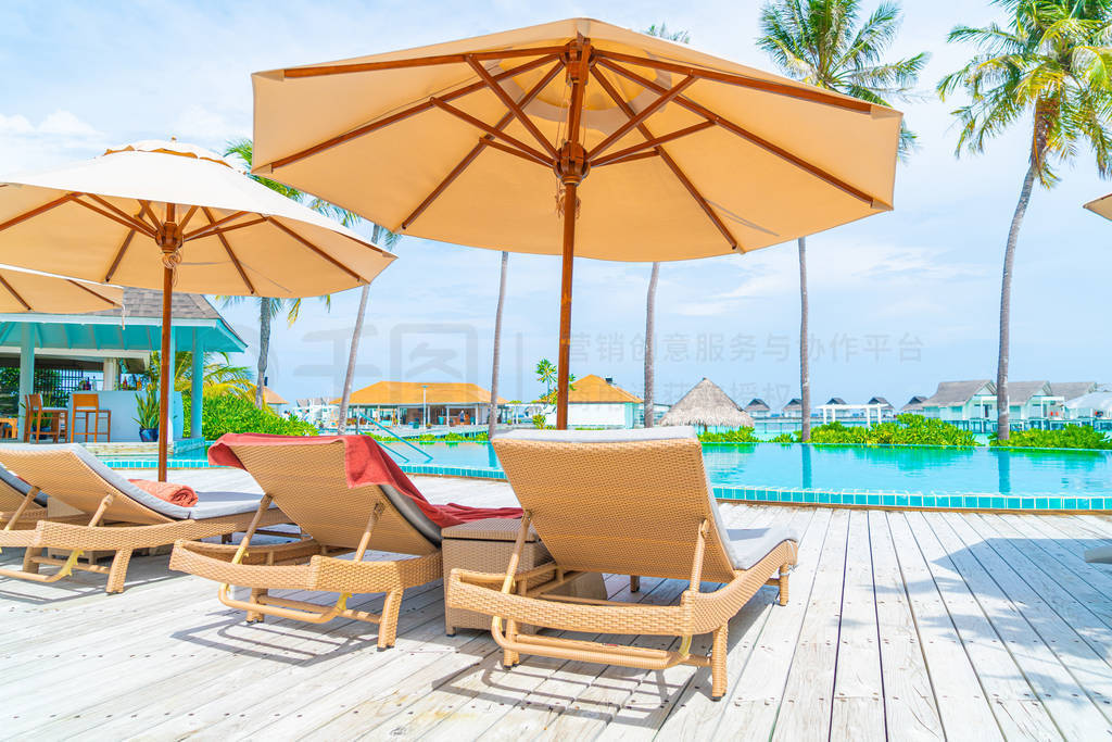 Umbrella and chair around swimming pool in resort hotel