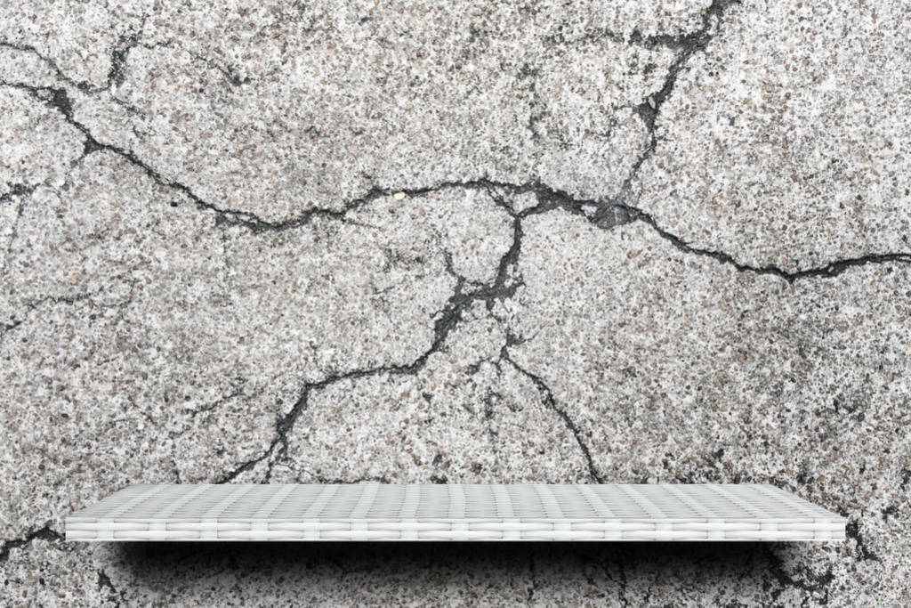 Empty white shelf on cracked gray concrete background for produc