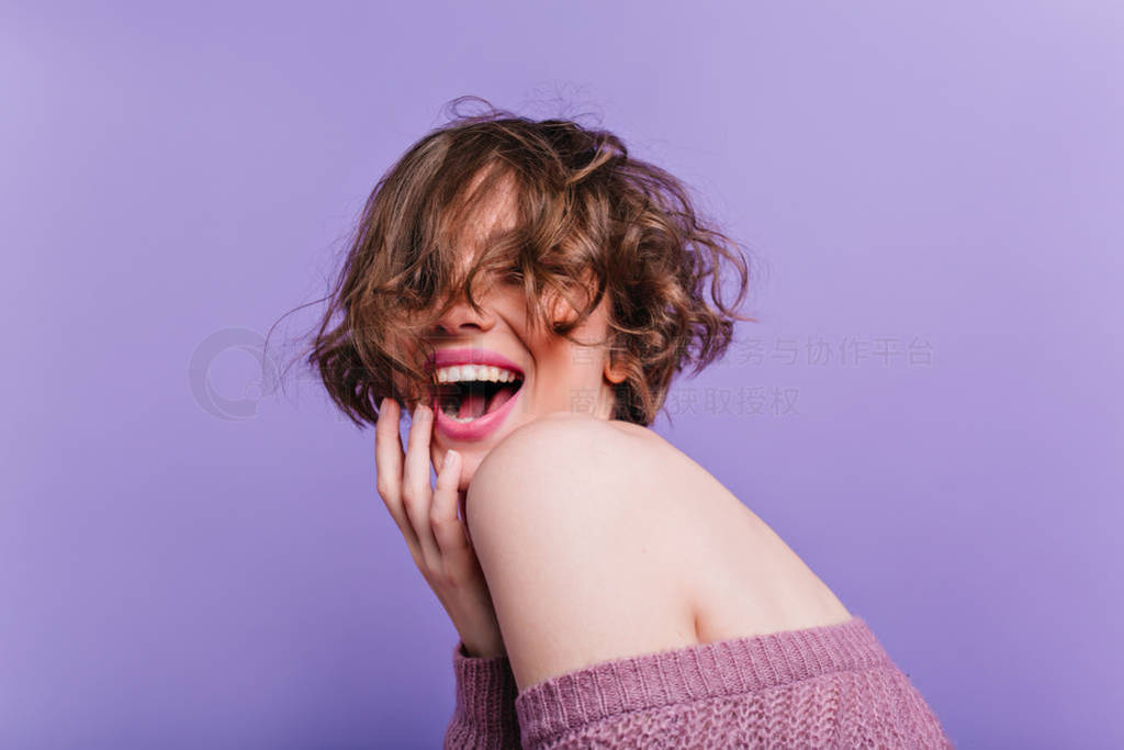 Enchanting female model with pale skin laughing on purple backgr