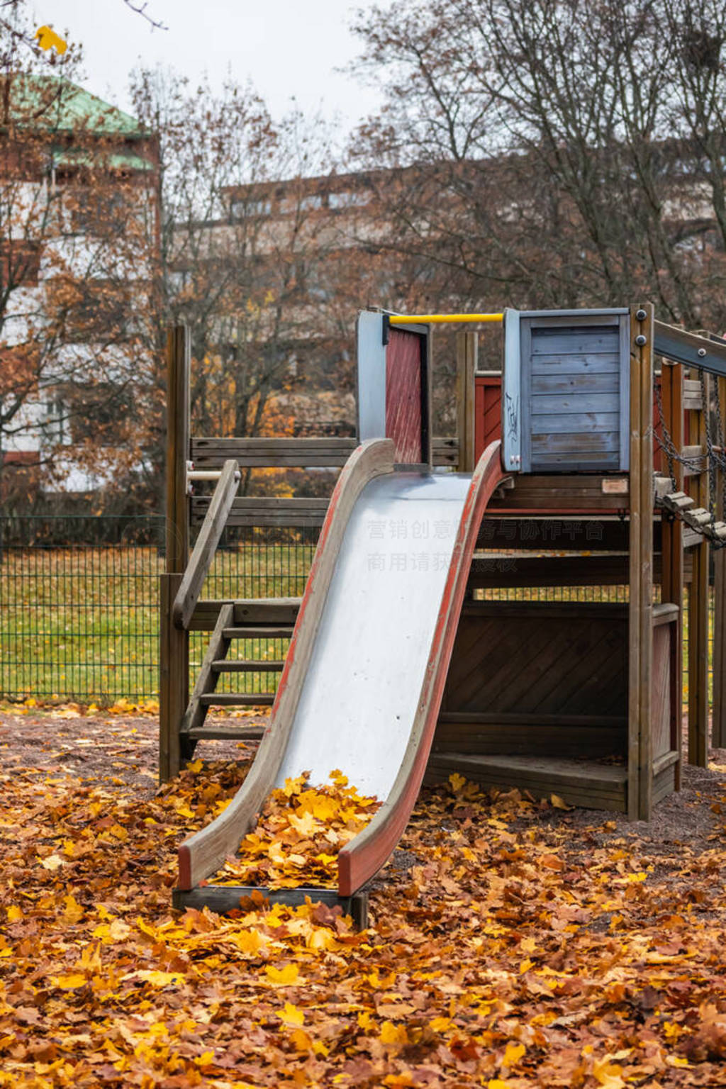 Empty old children slide with maple leaves at autumn day.