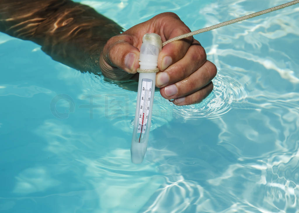 Closeup of swimming pool thermometer in man hand ,pool water is