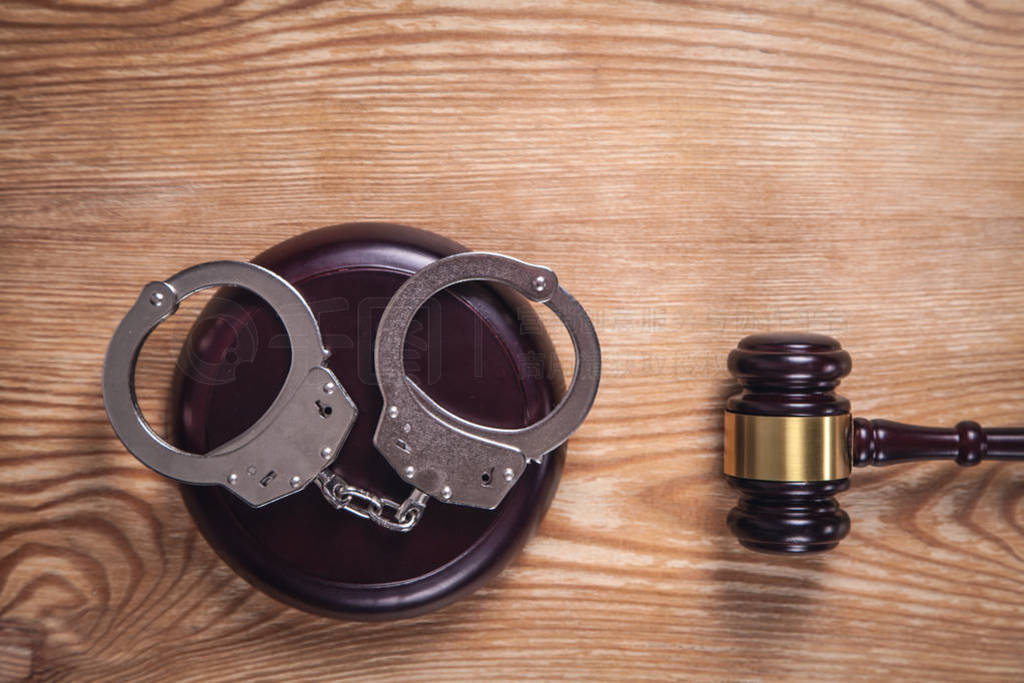 Metal handcuffs and judge gavel on wooden background. Crime and