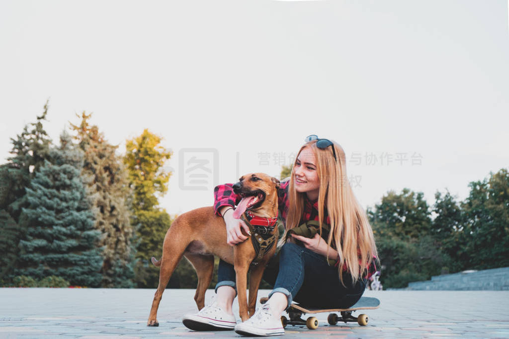 Teenage skater girl hugging her dog in urban environment.