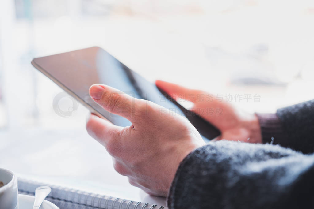 Human hands hold a tablet or e-book at a public place, close-up