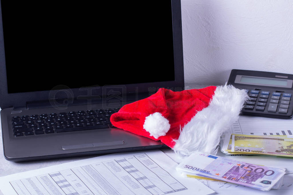 Desktop with laptop and charts. Santa hat