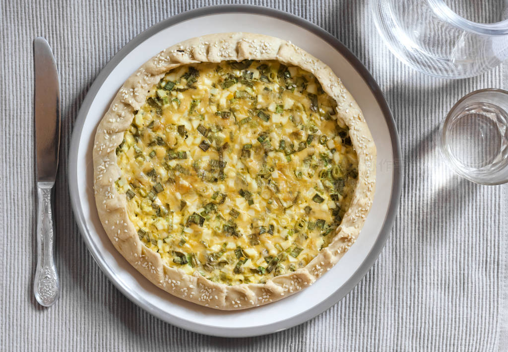 Tart with eggs and green onions on a plate