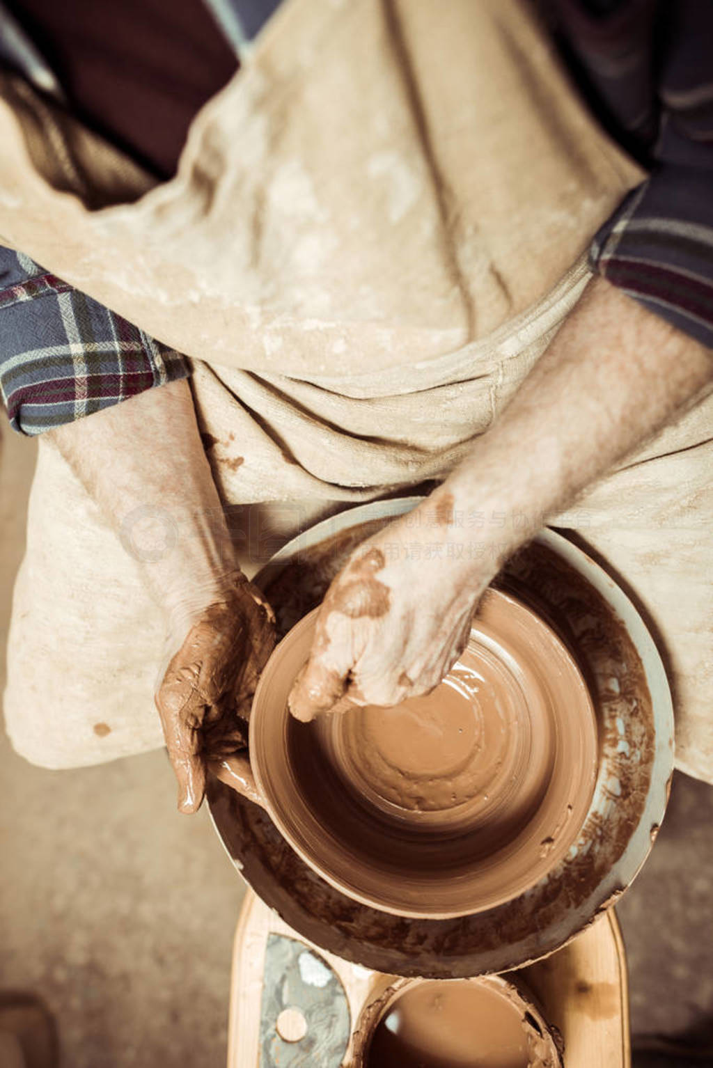 女陶工在陶工的轮子上工作，做一个花瓶。师傅用手在作坊里制作陶罐照片摄影图片_ID:351520042-Veer图库